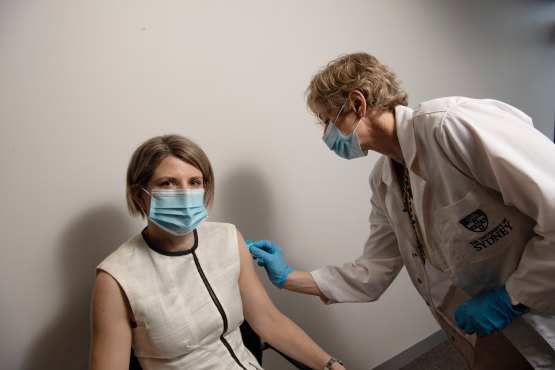 Professor Rachel Skinner and Ms Cristyn Davies use the Vaxxas device on each other. The device causes a "sensation" but is not painful.