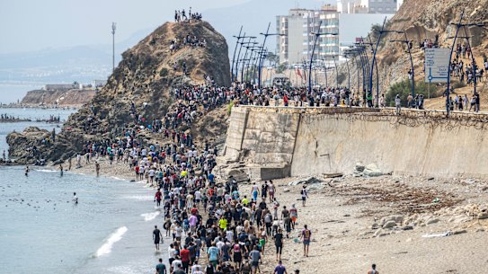 People walk on a beach after attempting to cross from Fnideq to Ceuta.