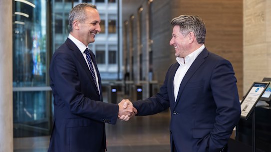 Nine chief executive Mike Sneesby and NRL chief executive Andrew Abdo shake hands in the foyer of the Nine headquarters in North Sydney.