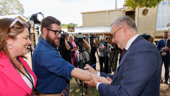 Anthony Albanese writes and signs a “No Change To WA GST” pledge on the arm of West Australian reporter Dylan Caporn in February 2024.