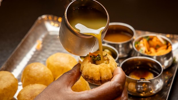 Pour mint-chilli-coriander water into pani puri.