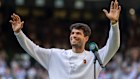 Carlos Alcaraz, sporting a Nike branded cardigan, salutes the crowd after his quarter-final win at Wimbledon. 