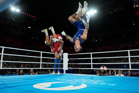 Uzbekistan’s Abdumalik Khalokov and Australia’s Charlie Senior flip after Khalokov won their men’s 57 kg semi-final boxing match.