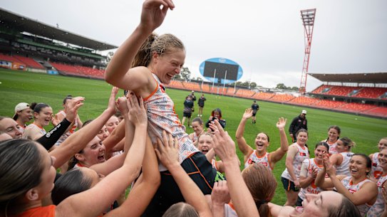 GWS Giants AFLW players lift Grace Kos in the air at a training session at ENGIE Stadium.