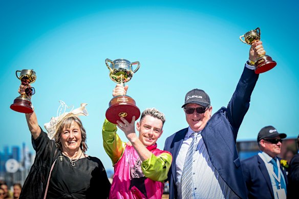 Jockey Robbie Dolan (centre) hoists the Melbourne Cup with trainers Sheila Laxon and John Symons.