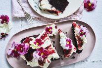 Chocolate loaf cake topped with mascarpone icing, red jam and flowers.