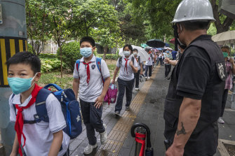 Pek çok okul Nisan ayından bu yana ilk kez Pekin'de yeniden açıldığından, 27 Haziran Pazartesi günü öğrenciler bir güvenlik görevlisi tarafından izleniyor. 