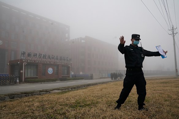 A security official moves journalists away from the Wuhan Institute of Virology in 2021.