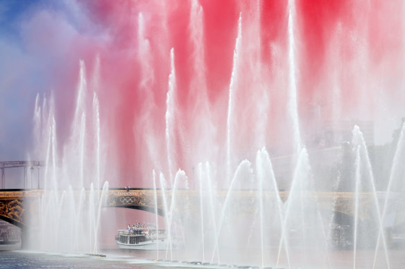 Team Greece begins the athletes’ parade past water jets and the water curtain under the Austerlitz Bridge on the Seine.