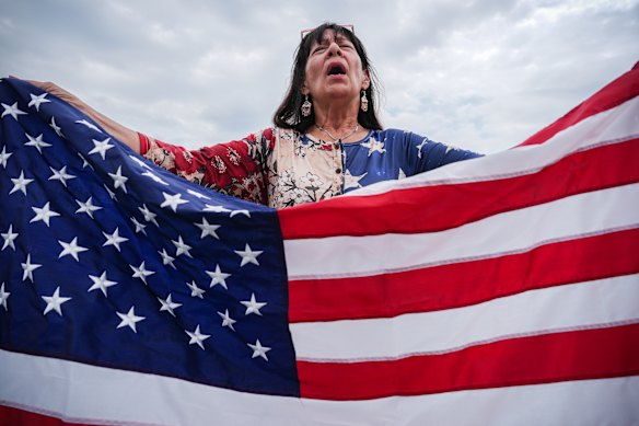 Kathy Fain, de Longview, Texas, segura uma bandeira dos EUA enquanto canta o hino nacional no evento. 