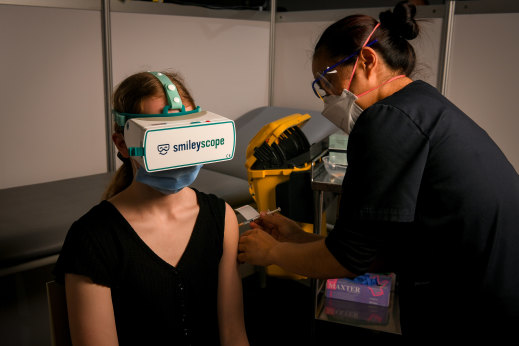 Christine, 16, wears a virtual reality headset as she gets her first COVID-19 jab.