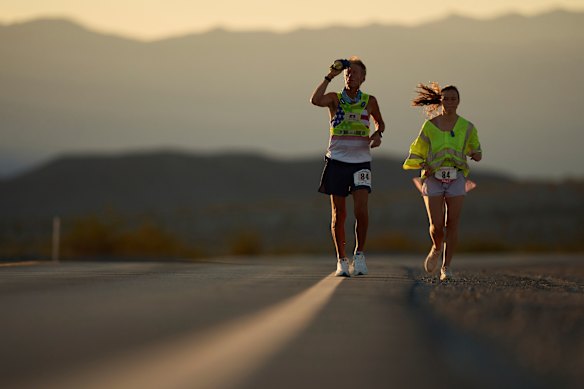 Westergaard, à esquerda, esfriou com água com uma assistência de ritmo da filha de Madison Westramgaard, enquanto o sol nasce em Badwater 135 Ultramarathone em 8 de julho.