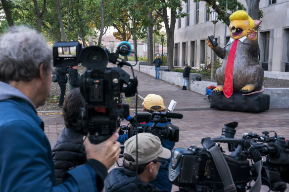 Media gathers around an inflatable rat styled after former President Donald Trump while waiting for the arrival of Steve Bannon, longtime ally of the former president, convicted of contempt of Congress.