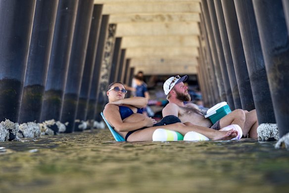 Os moradores Madi e Ryan se refrescam sob um píer em Altona Beach na quarta-feira.