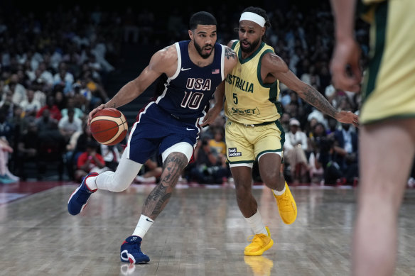 Boomers icon Patty Mills tries to defend US star Jayson Tatum on a drive to the basket.