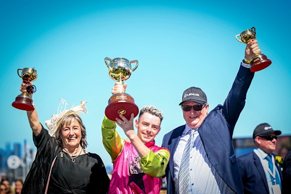 Jockey Robbie Dolan (centre) hoists the Melbourne Cup with trainers Sheila Laxon and John Symons.