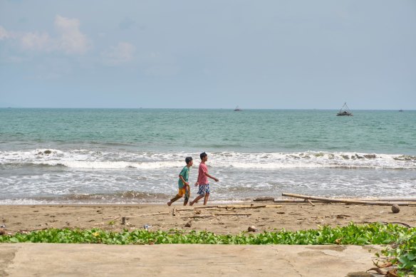 People walk along Citepus Beach, Palabuhan Ratu, Indonesia, where the group were trying to board a boat.