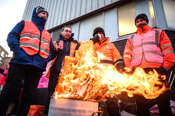 A group of striking postal workers stand around a fire as they picket outside a Royal Mail sorting office in London on December 14. Several unions are striking for better pay and conditions in Britain.