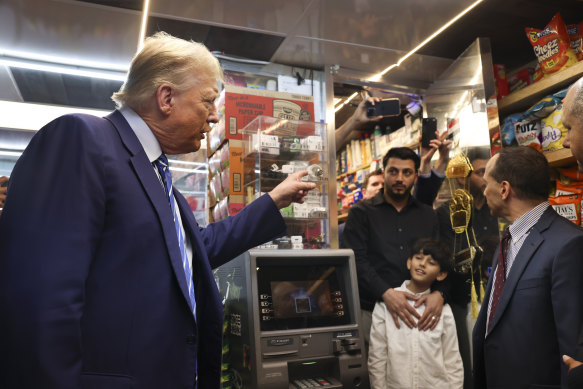 Former president Donald Trump talks with bodega owner Maad Ahmed, centre, during a campaign stop at his New York store on Tuesday. 