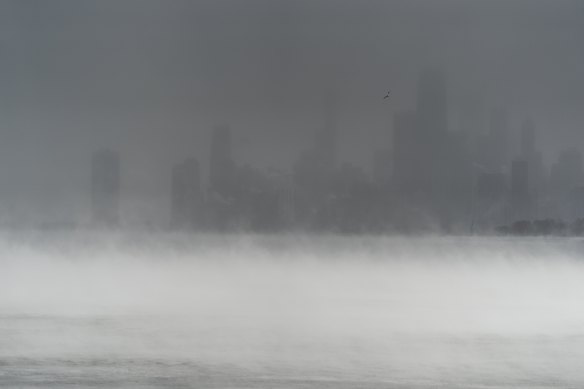 The downtown Chicago skyline is obscured by blowing snow and steam rising from Lake Michigan.