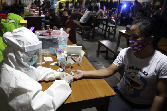 Medical workers take blood samples from a customer during a rapid test for the new coronavirus at a cafe in Surabaya, East Java, Indonesia.