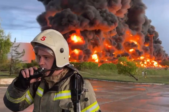 A firefighter speaks on a walkie talkie as smoke and flame rise from a burning fuel tank in Sevastopol, Crimea on Saturday.