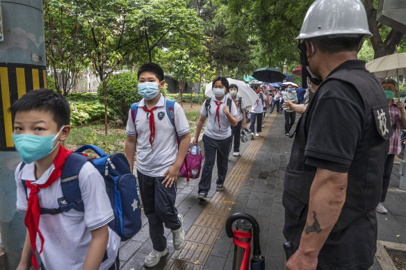 Students are watched by a security guard on Monday, June 27, as many schools reopened in Beijing for the first time since April. 