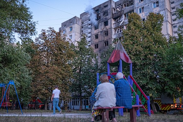 Residents look on as an apartment building smoulders after a Russian air raid.