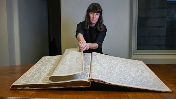Curator Kate Rhodes with an original copy of The Age opened at the pages reporting on the Kelly Gang’s shootings.
