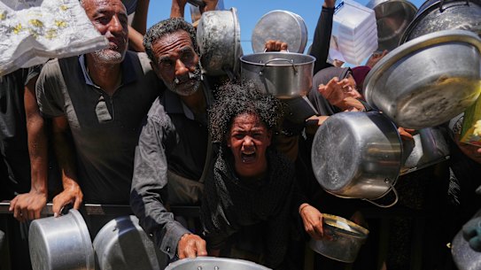 Palestinians struggle to get donated food at a community kitchen in Khan Younis on Monday.