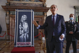 French ambassador to Italy, Christian Masset, unveils the recovered stolen artwork by British artist Banksy, that was painted on a door as a tribute to the victims of the 2015 terror attacks at the Bataclan music hall in Paris.