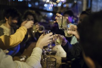 People toast as they enjoy their last evening for now on a bar terrace in Paris.