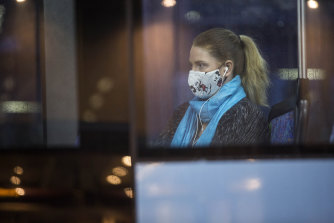 A woman sits on her bus at Parramatta Station wearing a mask.