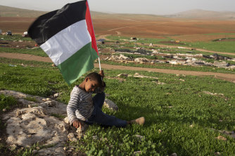 A Palestinian Bedouin boy holds a Palestinian flag after Israeli troops demolished tents and other structures of the Khirbet Humsu hamlet in the Jordan Valley in the West Bank on Wednesday.