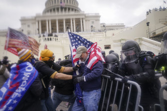 İsyancılar 6 Ocak 2021'de Washington'daki Capitol'deki bir polis bariyerini aşmaya çalışıyor.