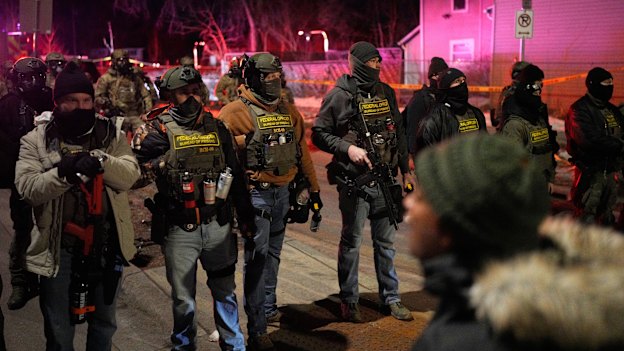 Federal law enforcement officers stand against protesters after a shooting in Minneapolis on Wednesday.