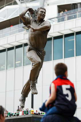 Football fans stop at the Shane Warne statue outside the MCG.