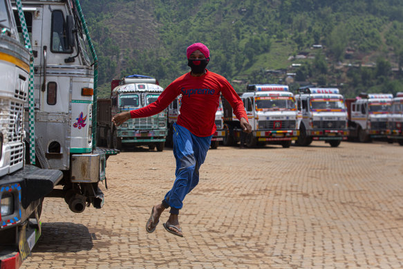 A stranded truck operator playfully jumps near parked trucks during the nationwide lockdown in Gauhati, India.