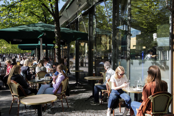People sit at tables outside a cafe at Kungstrdgrden in Stockholm, Sweden, earlier this year.