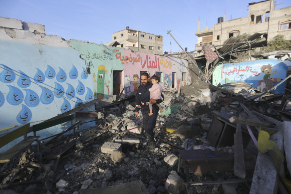 Palestinians walk by a building destroyed in Israeli bombardment overnight in Rafah, Gaza Strip, on Friday.