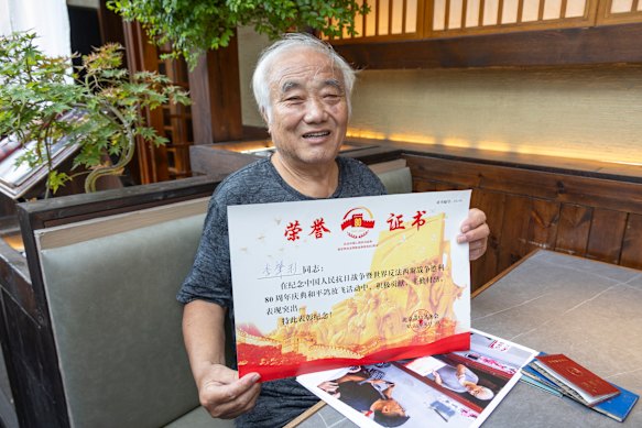 Li shows the certificate of honour he received for contributing pigeons to the 80,000-strong flock released at the military parade in Beijing last year. 