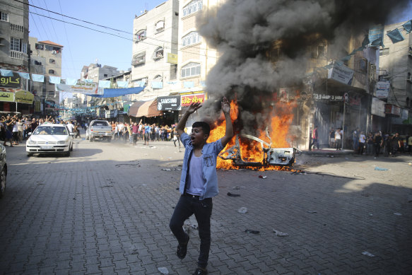 A Palestinian reacts by a burning Israeli civilian car taken from Kfra Azza kibbutz in Beit Lahiya in the Gaza Strip.