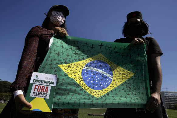 Demonstrators hold a Brazilian flag marked with black crosses during a protest demanding President Jair Bolsonaro be impeached, in front of the National Congress in Brasilia.