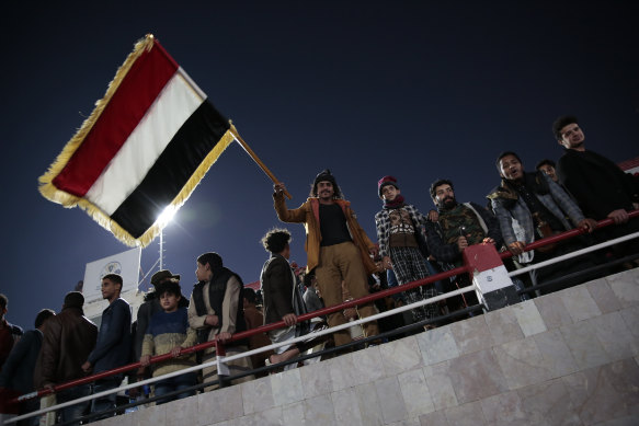 A Yemeni man holds his national flag as he and others watch the final of West Asian Junior Championships between Yemen and Saudi Arabia in Sanaa, Yemen.