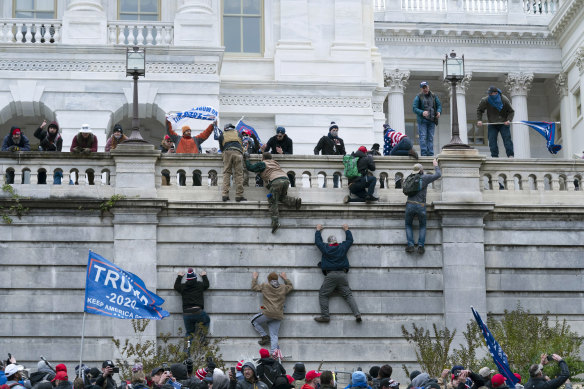 Protesters scale a wall at the US Capitol on January 6 last year.