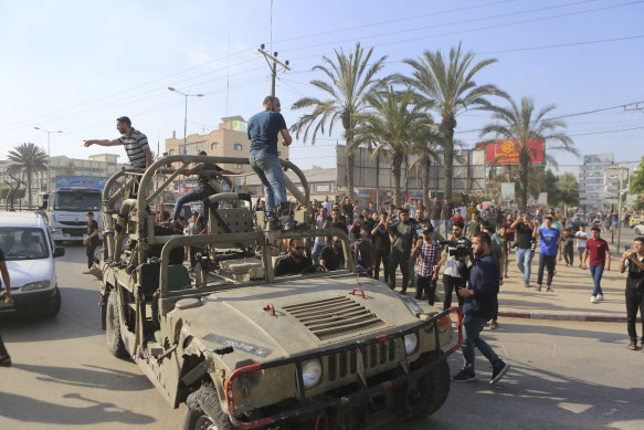 Palestinians ride on an Israeli military vehicle taken from an army base overrun by Hamas militants near the Gaza Strip fence, in Gaza.