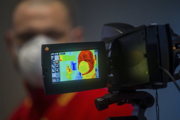 An airline passenger is checked with a thermal imaging camera for signs of coronavirus.