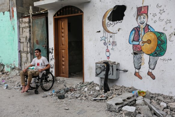 A man in a wheelchair outside a  building damaged by Israeli air raids.