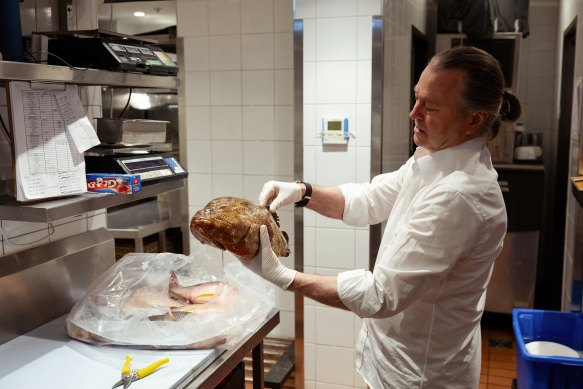 Perry examining fish at Margaret, the restaurant he opened in late 2021.