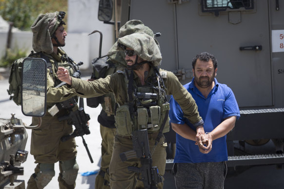 Israeli soldiers make one of several arrests of Palestinians on May 12 after a soldier of their occupation force was killed by a rock thrown from a rooftop in the West Bank village of Yabad. 